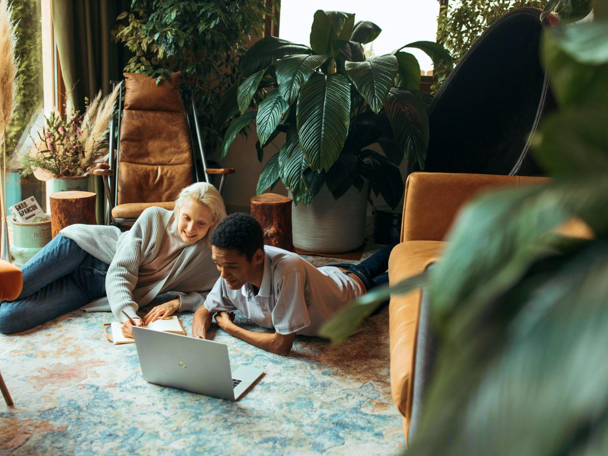 Two colleagues with laptop on a rug in a relaxed setting